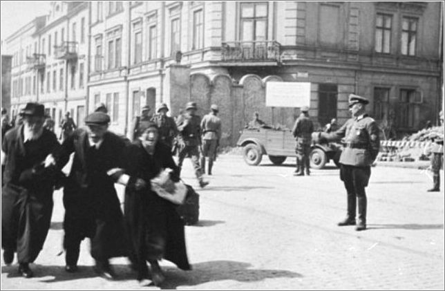 Three elderly Jews walk arm-in-arm through the streets of Krakow during the final liquidation action of the ghetto